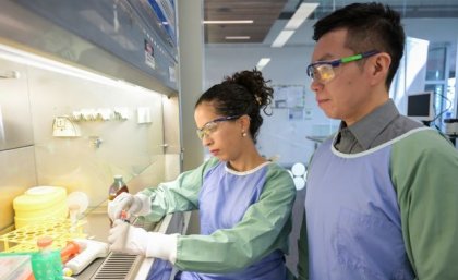 Professor Di Yu with colleague Dr Emely Hernández in the lab. Two scientists in lab coats and goggles working in a lab.